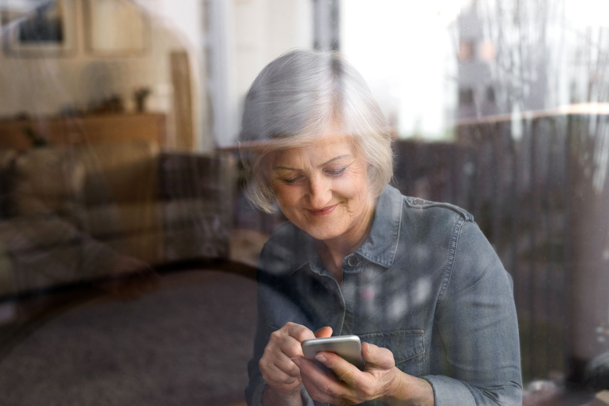 Elderly woman typing into mobile phone